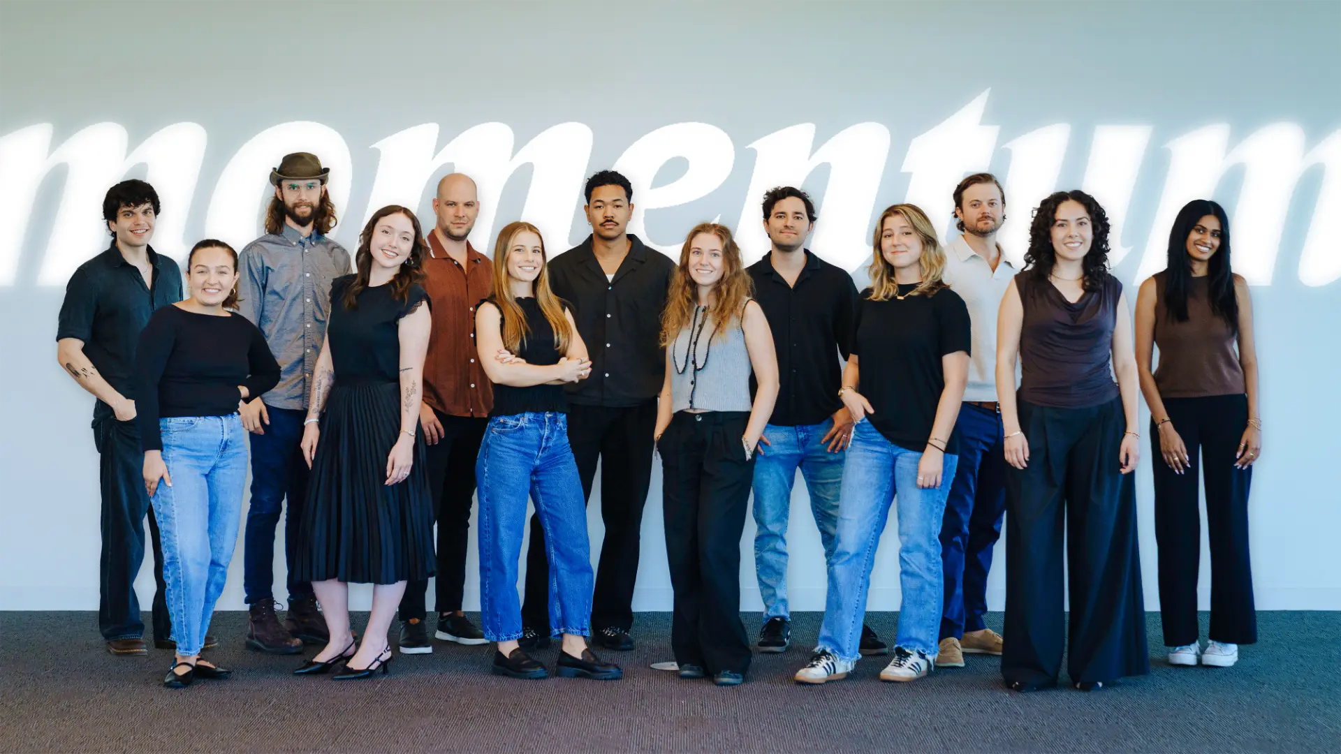 The Momentum Marketing Company team standing in front of the momentum wordmark